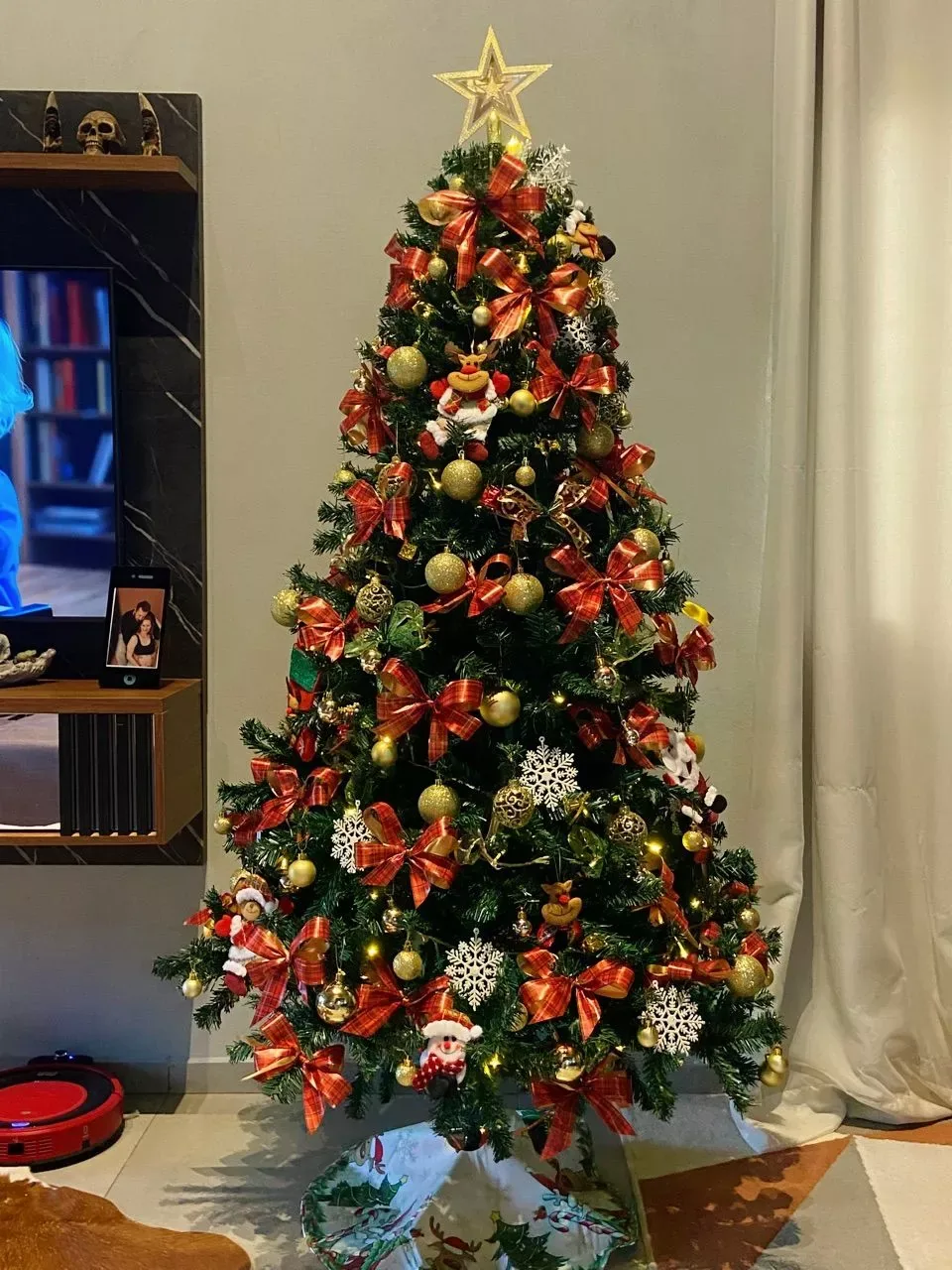 Árvore decorada com laços vermelhos, bolas douradas e estrela
